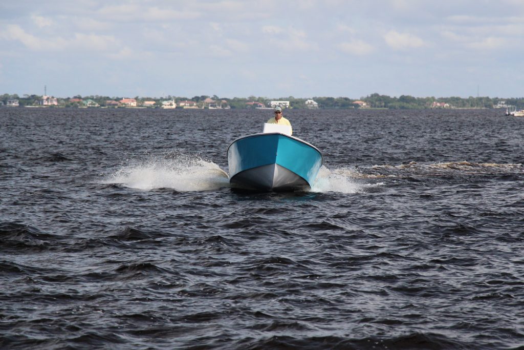 Front view of a boston whaler blue Atlas Boatworks 23F center console fishing boat running in choppy water. 150hp yamaha outboard engine on the back.