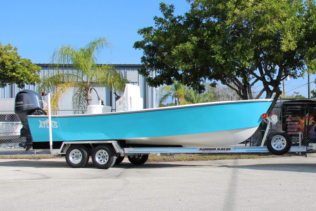 Side view of a boston whaler blue Atlas Boatworks 23F center console fishing boat on a trailer.