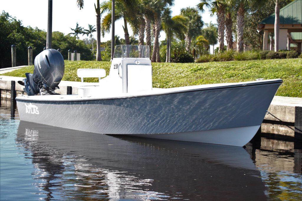 Side view of a whisper grey Atlas Boatworks 23F center console tied to a seawall. 200hp yamaha outboard engine on the back tilted up.