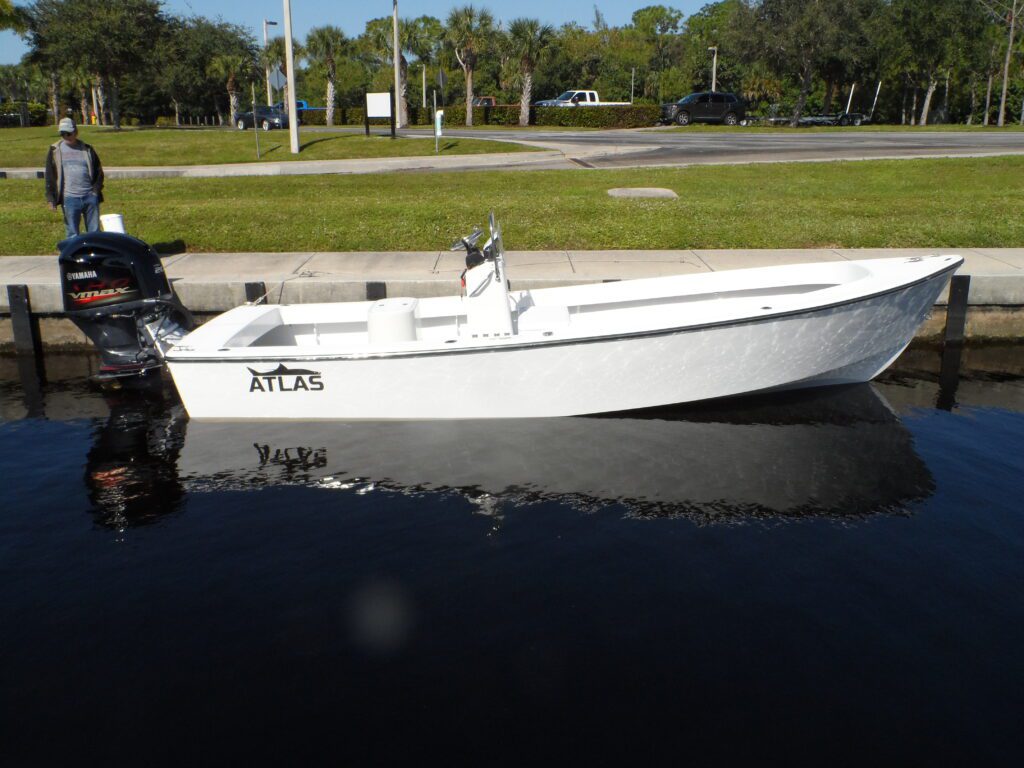 Side view of a white Atlas 23F center console fishing boat tied to a seawall. Yamaha VMax engine on the back