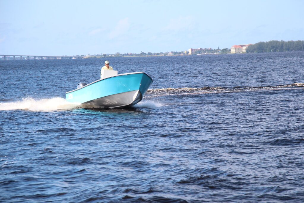 Front view of a boston whaler blue Atlas Boatworks 23F center console fishing boat running in choppy water. 150hp yamaha outboard engine on the back.