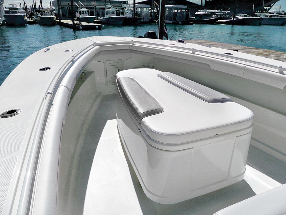 Coffin-box style cooler on the front deck of an offshore fishing boat. Has grey and white cushion on top.