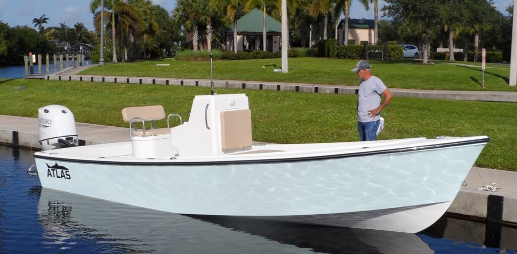 Front view of an ice blue Atlas Boatworks 23F tied to a seawall. A man in the background inspects the front of the boat. White Suzuki 200hp engine on the back.
