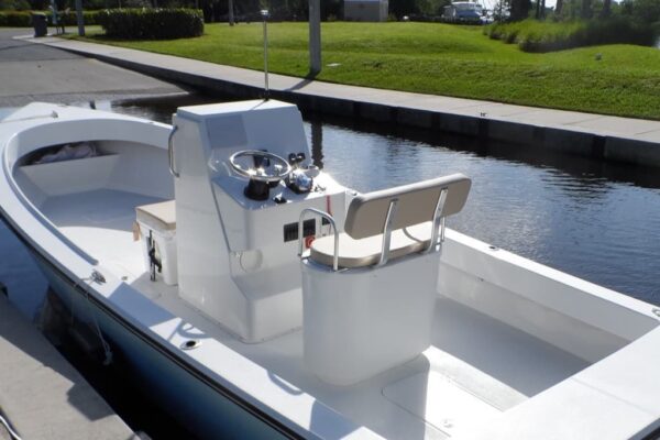 View of Atlas Boatworks 23F center console fishing boat from the port stern. Tan cushions on the livewell and cooler seat.