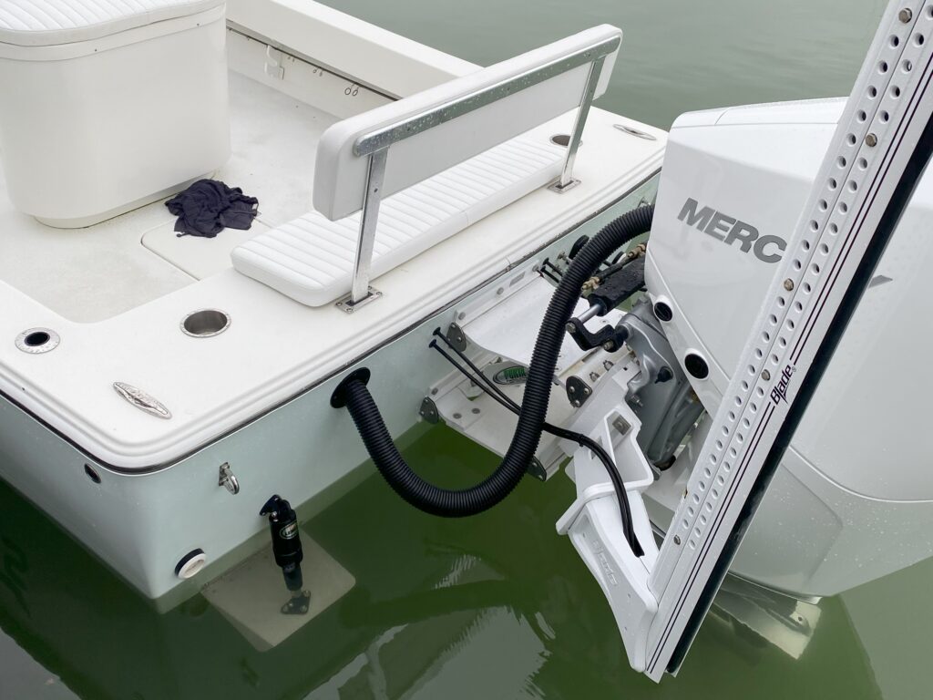 Stern of ice blue Atlas Boatworks 23F with white porta bracket, white 10-foot blade power pole shallow-water anchors and Mercury 200XS motor.