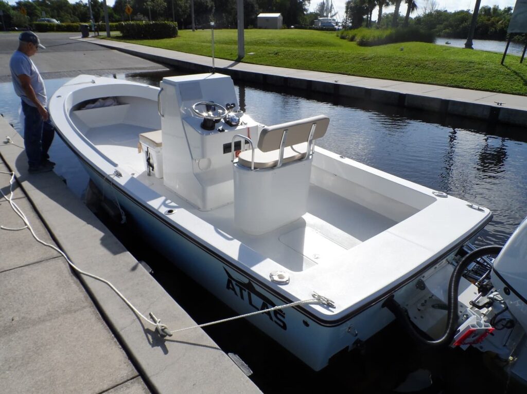 View of Atlas Boatworks 23F center console fishing boat from the port stern. Tan cushions on the livewell and cooler seat.