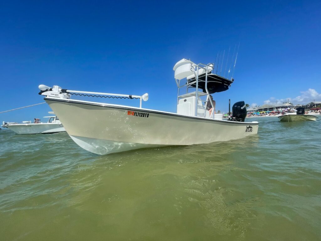 Side view of tan Atlas Boatworks 23F center console fishing boat at anchor. It has a half tower installed with 2nd station up top.