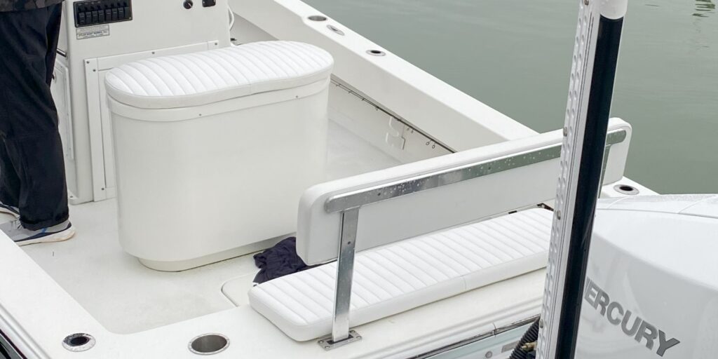 View of Atlas Boatworks 23F center console fishing boat rear bench seat with white cushions.