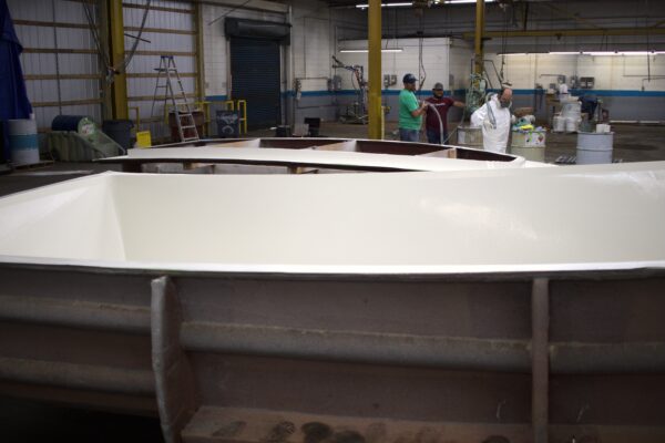 The white hull in a mold sits in front of a white deck cap in the background