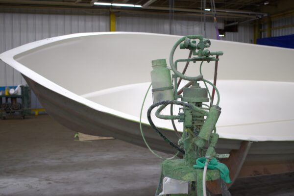 A gelcoat machine sits in front of a boat mold.