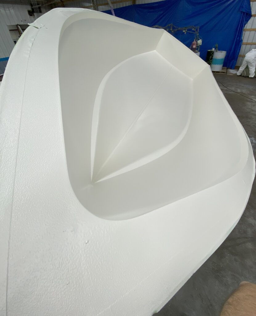 A picture of a white boat hull in the mold from the bow back.