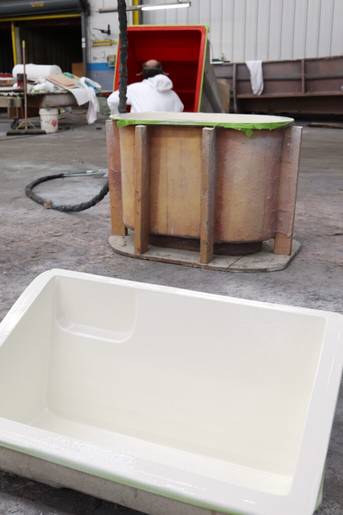 small boat parts are lined up while gelcoat is sprayed in each