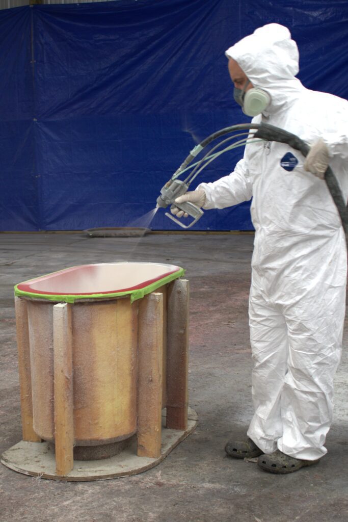 A worker sprays gelcoat into a livewell mold