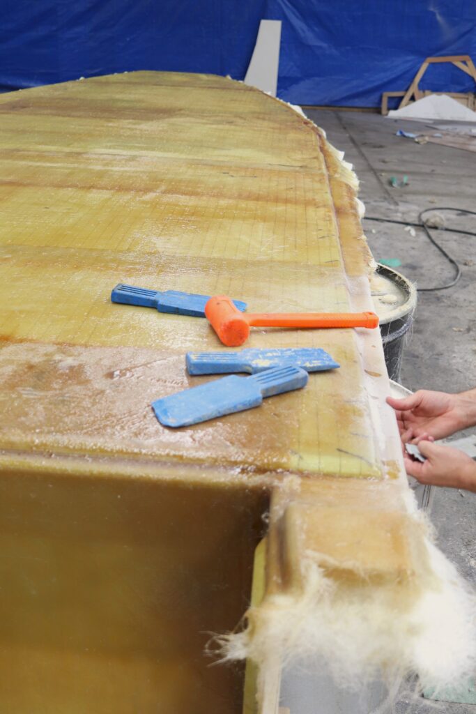 Wedges and a hammer sit on the top of a boat deck in a mold