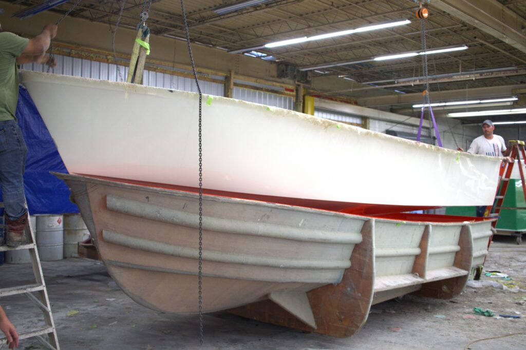 A boat hull hangs above the mold that it came out of