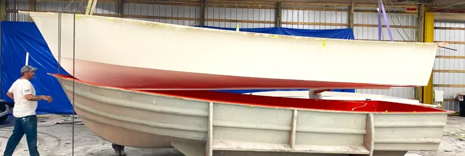 A boat hull hangs above the mold