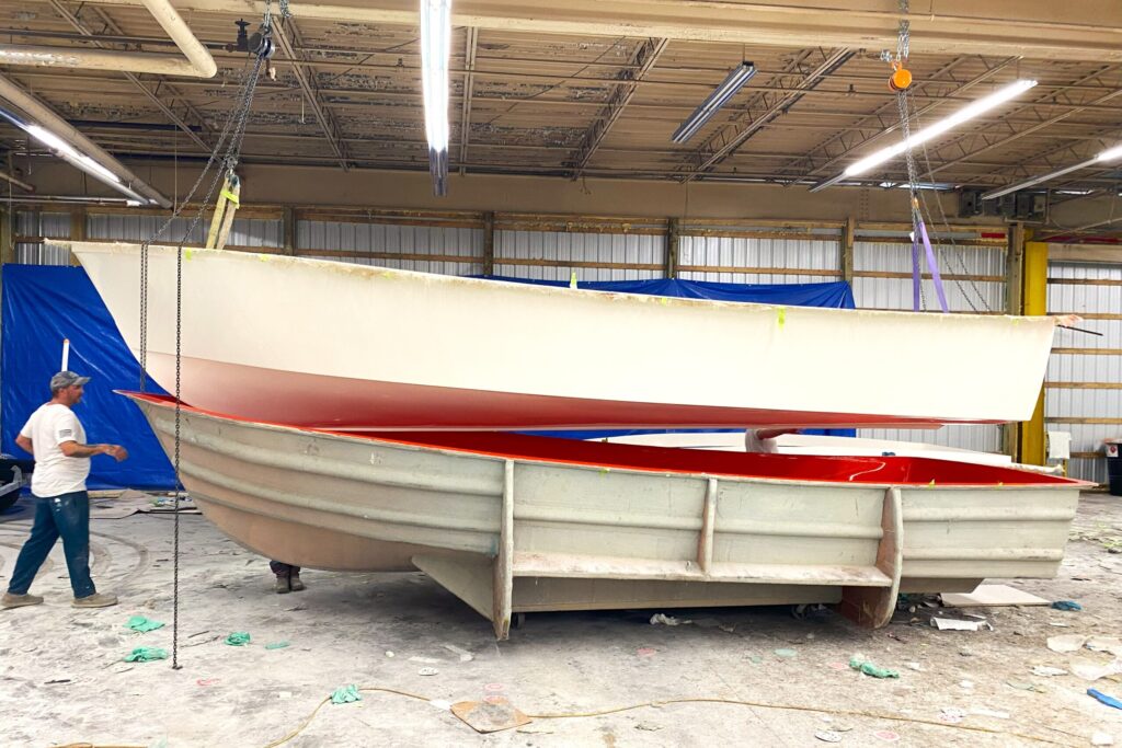 A boat hull hangs above the mold