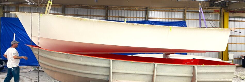 A boat hull hangs above the mold