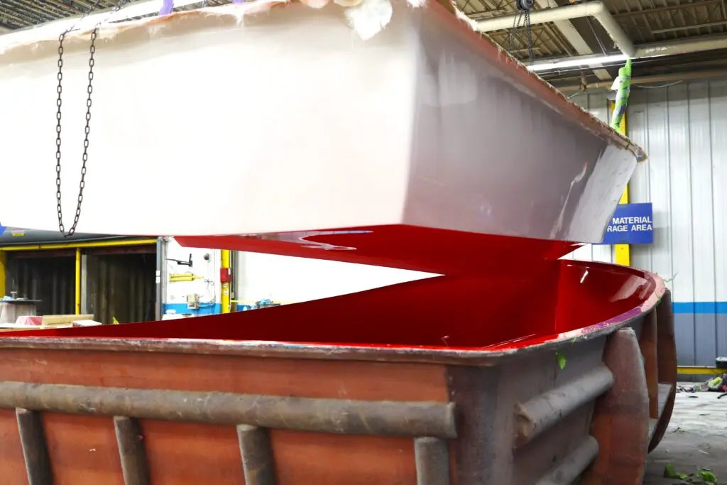 The hull of an Atlas Boatworks 23F bay boat hangs above the mold it just came out of