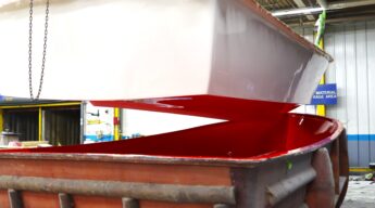 The hull of an Atlas Boatworks 23F bay boat hangs above the mold it just came out of