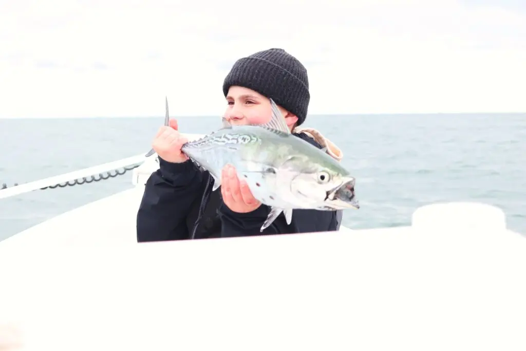 A kid holds a false albacore on an Atlas Boatworks 23F bay boat