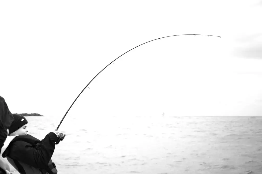 a kid fights a big fish on a bent fishing rod