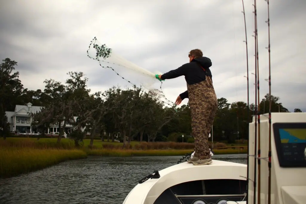 A fisherman throws a castnet off the bow of an Atlas Boatworks 23F bay boat